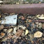 The silver rectangle is the top of an electrical junction box, buried in the dirt. This will cause the box to become corroded, and will eventually disintegrate into pieces.