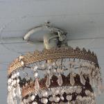 This chandelier needs to be hanging from a lighting outlet box. Someone has installed it with 120volt connections next to combustible material (wooden ceiling), not to mention there are live exposed connections on the sides of the porcelain lamp socket. 